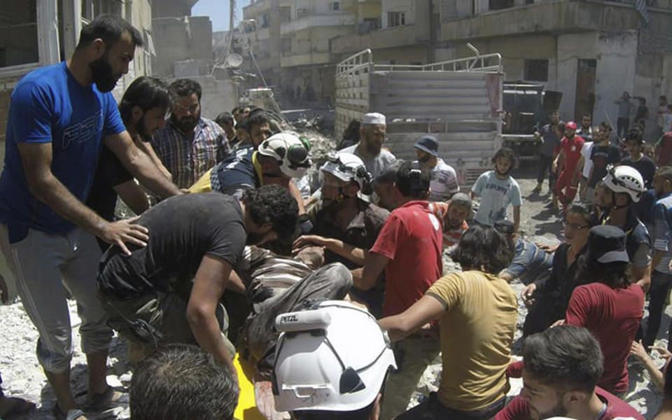 This photo provided by the Syrian Civil Defense White Helmets, shows Syrian White Helmet civil defense workers and civilians carry an injured man on a stretcher after an airstrike hit the northern town of Ariha, in Idlib province, Syria, Sunday, July 28, 2019. Syrian opposition activists and a war monitor say five people have been killed in airstrikes on a town in the country's northwest as the government keeps up its deadly air campaign on the rebel-controlled region. (Syrian Civil Defense White Helmets via AP)