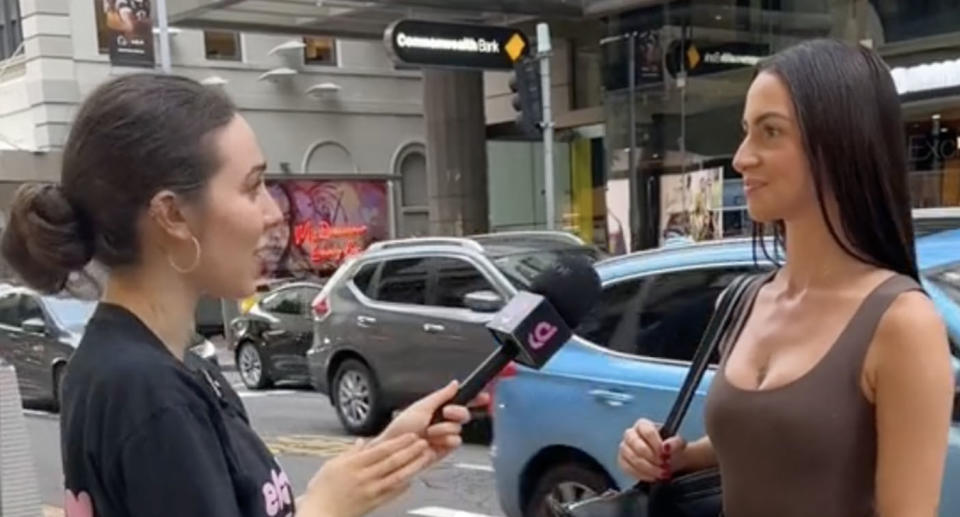 Worker standing in the street answering what she gets paid. 