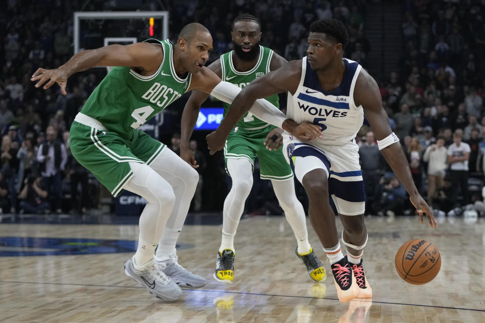 Minnesota Timberwolves guard Anthony Edwards dribbles down the court as Boston Celtics center Al Horford, left, and guard Jaylen Brown, center, defend during the first half of an NBA basketball game, Monday, Nov. 6, 2023, in Minneapolis. (AP Photo/Abbie Parr)