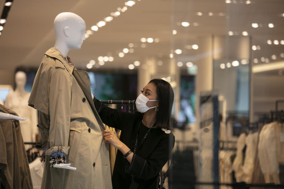 FILE - In this March 1, 2020, file photo, a department store employee with a mask dresses a mannequin in Tokyo. Japan's economic growth plunged into recession in the first quarter as the coronavirus pandemic squelched production, exports and spending, and fears are growing worse times may lie ahead, according to a report on Monday, May 18, 2020. (AP Photo/Jae C. Hong, File)