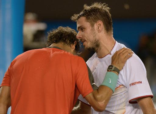 El tenista suizo Stanislas Wawrinka (dcha) consuela tras su victoria al español Rafael Nadal, en el Abierto de Australia, el 26 de enero de 2014, donde el español, número uno del mundo, cayó ante el suizo en cuatro sets y lesionado de la espalda (AFP | Greg Wood)