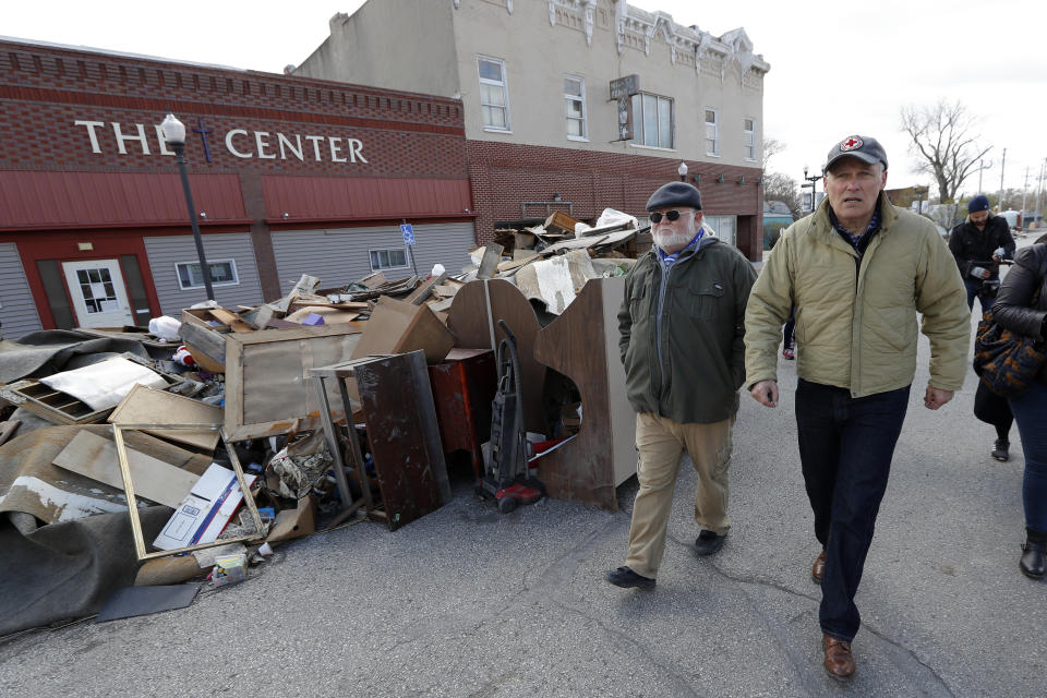 2020 Democratic presidential candidate Washington Gov. Jay Inslee, right, walks with climate analyst John Davis, of Hamburg, Iowa, while touring flood damage, Friday, April 12, 2019, in Hamburg, Iowa. (AP Photo/Charlie Neibergall)