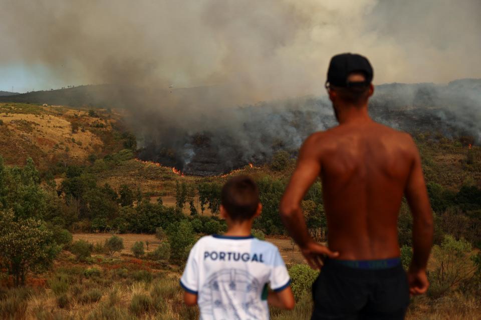 A man and a child watch a wildfire in Carrapichana, Celorico da Beira, Portugal (REUTERS)