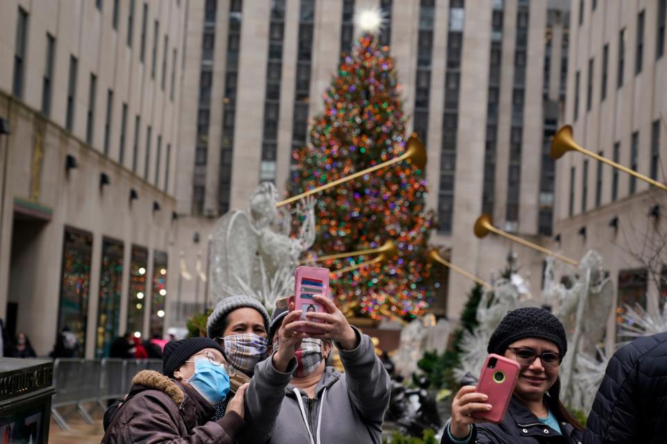 People take pictures of themselves with the Rockefeller Center Christmas tree in New York on Christmas day, Friday, Dec. 25, 2020. The coronavirus upended Christmas traditions, but determination and imagination kept the day special for many.