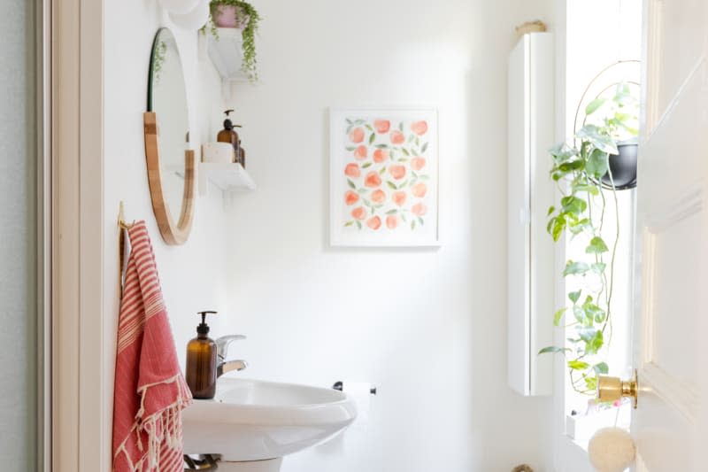 A white half bath with minimalist decor and a hanging plant