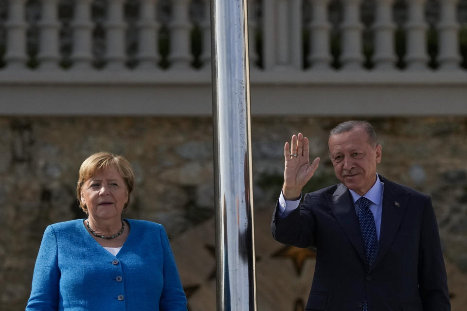 Turkish President Recep Tayyip Erdogan, flanked by German Chancellor Angela Merkel, waves to the media on the occasion of their meeting at Huber Villa presidential palace, in Istanbul, Turkey, Saturday, Oct. 16, 2021. (AP Photo/Francisco Seco)