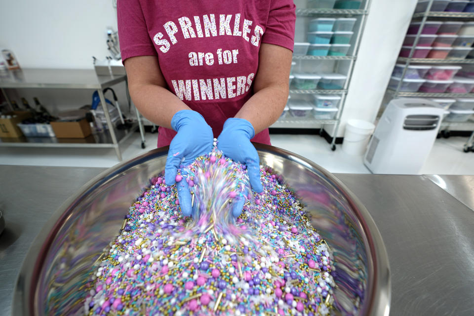 In this Tuesday, Aug. 13, 2019, photo Elizabeth Butts, owner of Sprinkle Pop, a company based in Houston that makes upscale sprinkles for bakers, mixes a batch of Unicorn sprinkles in Houston. Butts is building out and equipping a 10,000 foot facility for storage and shipping. She's reinvesting the company's profits rather than seeking investors, which will make it easier for her to run the company, but she also doesn't want to burden her company with debt. (AP Photo/David J. Phillip)