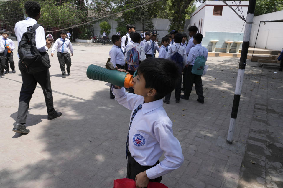 A student drinks water prior to leaving after attending their school as authorities announced reduced school hours due to soaring temperature, in Lahore, Pakistan, Tuesday, May 21, 2024. Authorities in Pakistan on Tuesday urged people to stay indoors as the country is hit by an extreme heat wave that threatens to bring dangerously high temperatures and yet another round of glacial-driven floods. (AP Photo/K.M. Chaudary)