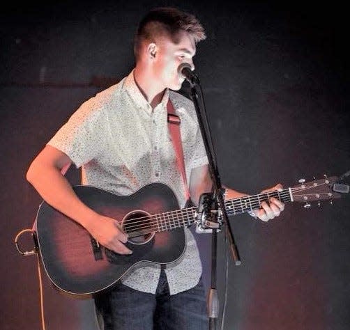 Gus Johnson playing guitar at a recent gig. Johnson, 17, writes most of the songs he and his brother Phin perform.