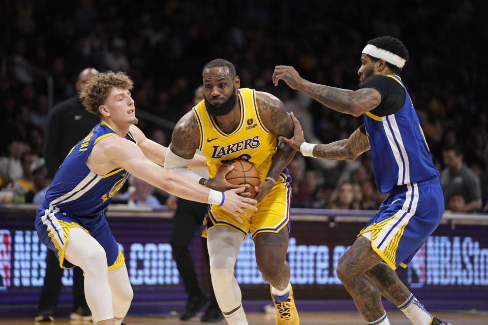 Los Angeles Lakers forward LeBron James, center, tries to go up for a shot as Golden State Warriors guard Brandin Podziemski, left, and guard Gary Payton II defend during the first half of an NBA preseason basketball game Friday, Oct. 13, 2023, in Los Angeles. (AP Photo/Mark J. Terrill)