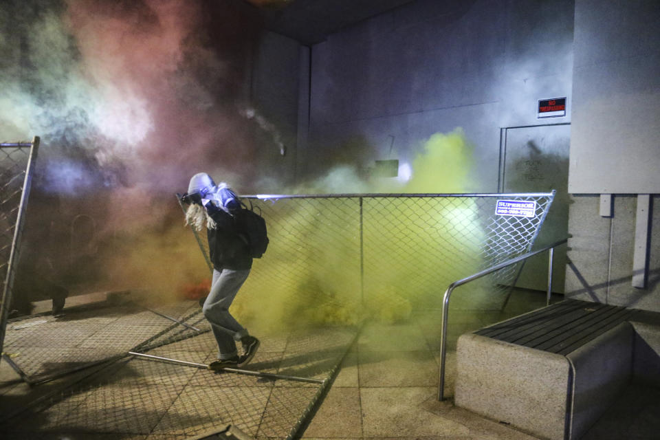 A protesters runs as police respond during a demonstration, Friday, July 17, 2020 in Portland, Ore. Militarized federal agents deployed by the president to Portland, Oregon, fired tear gas against protesters again overnight as the city’s mayor demanded that the agents be removed and as the state’s attorney general vowed to seek a restraining order against them. (Dave Killen/The Oregonian via AP)