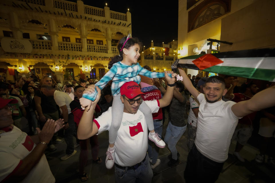 Moroccan and Palestinian soccer fans dance at the Souq Waqif during the FIFA World Cup, in Doha, Qatar on Sunday Dec. 4, 2022. (AP Photo/Ashley Landis)