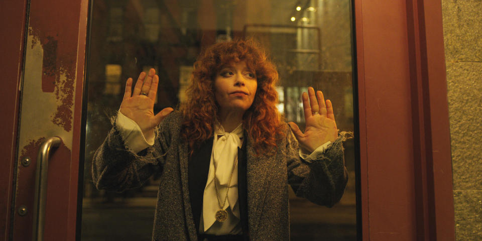 A red-haired woman stares through a glass door