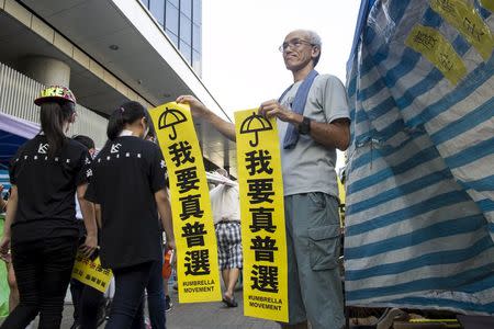 A pro-democracy protester hold banners which read "I want real universal suffrage" during a demonstration outside Legislative Council in Hong Kong, China June 17, 2015. REUTERS/Tyrone Siu