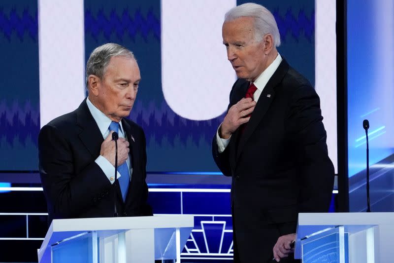New York City Mayor Mike Bloomberg (L) and former Vice President Joe Biden cover their microphones as they chat during a break at the ninth Democratic 2020 U.S. Presidential candidates debate at the Paris Theater in Las Vegas