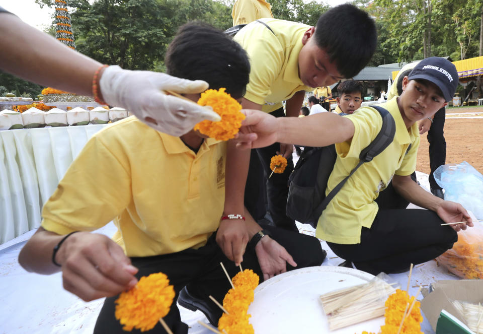 Members of the Wild Boars soccer team who were rescued from a flooded cave, prepare a flower for a religious ceremony near the Tham Luang cave in Mae Sai, Chiang Rai province, Thailand Monday, June 24, 2019. The 12 boys and their coach attended a Buddhist merit-making ceremony at the Tham Luang to commemorate the one-year anniversary of their ordeal that saw them trapped in a flooded cave for more than two weeks. (AP Photo/Sakchai Lalit)