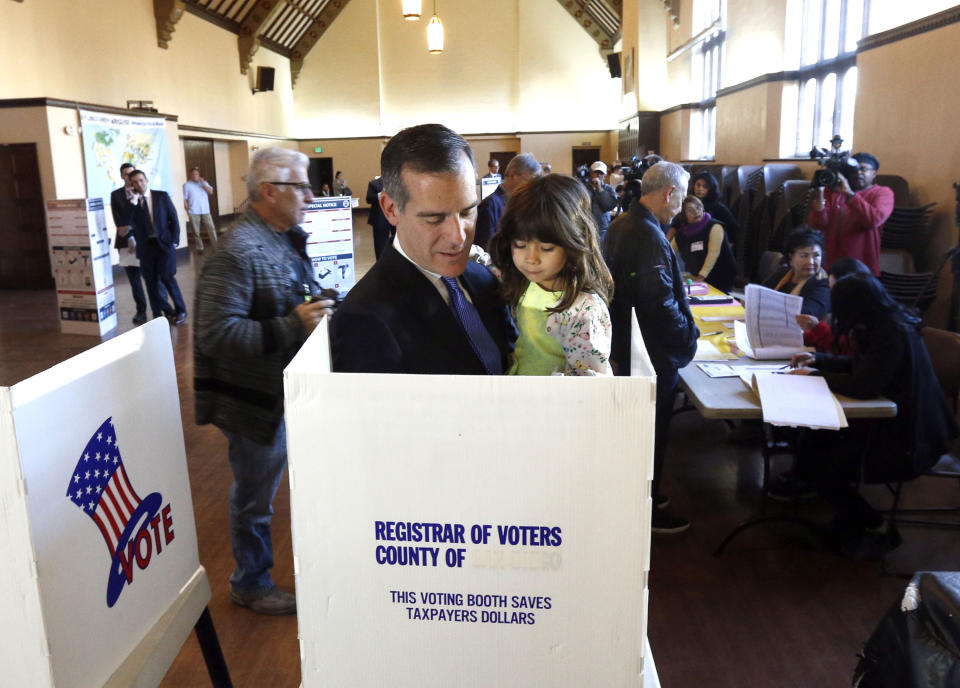 FILE - In this March 7, 2017, file photo, Los Angeles Mayor Eric Garcetti votes along with his daughter, Maya, in Los Angeles. Garcetti said Thursday, Dec. 17, 2020, that his 9-year-old daughter, Maya, has tested positive for COVID-19, and that he and his wife are quarantining at home. Garcetti said his daughter Maya felt ill on Monday, developed a fever and tested positive for COVID-19. He said he and his wife, Amy, have tested negative. Garcetti also said that he told the incoming Biden Administration earlier in the week that he would not leave Los Angeles. (AP Photo/Nick Ut, File)