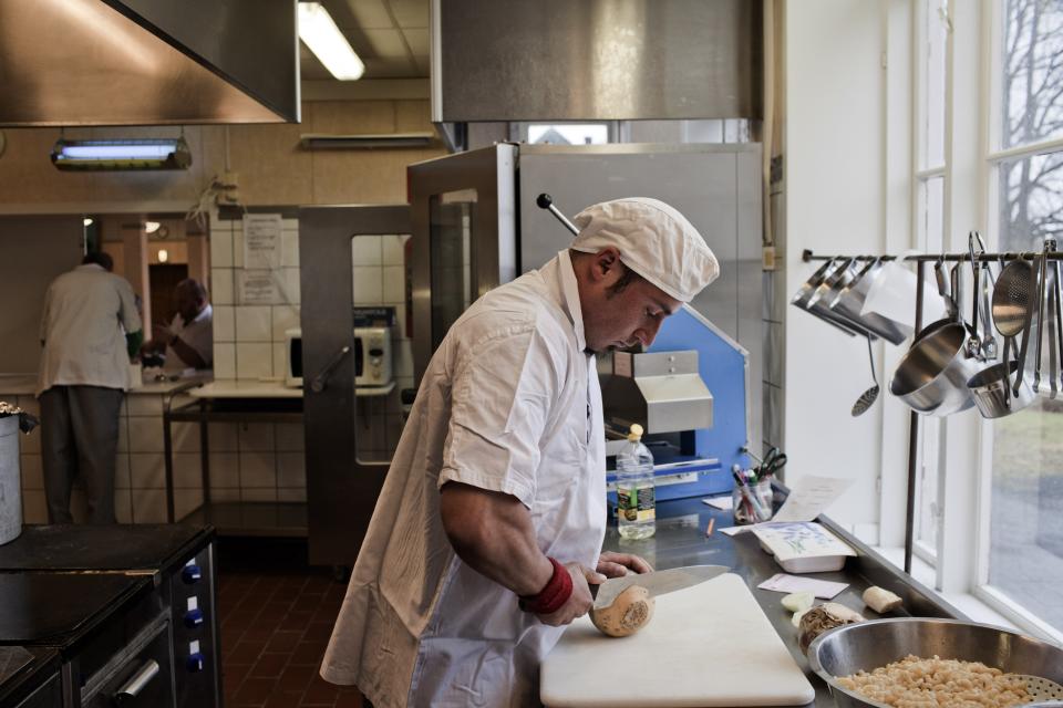 BASTOY ISLAND, HORTEN, NORWAY - APRIL 12:  Jan Vider, 28-years-old sentenced to twelve months for crime related to narcotics is seen working in the prison kitchen in Bastoy Prison on April 12, 2011 in Bastoy Island, Horten,  Norway. Bastoy Prison is a minimum security prison located on Bastoy Island, Norway, about 75 kilometers (46 mi) south of Oslo. The facility is located on a 2.6 square kilometer (1 sq mi) island and hosts 115 inmates. Arne Kvernvik Nilsen, governor of the prison, leads a staff of about 70 prison employees. Of this staff, only five employees remain on the island overnight.  Once a prison colony for young boys, the facility now is trying to become 'the first eco-human prison in the world.' Inmates are housed in wooden cottages and work the prison farm. During their free time, inmates have access to horseback riding, fishing, tennis, and cross-country skiing. (Photo by Marco Di Lauro/Reportage by Getty Images)