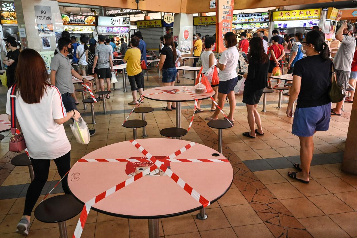 People queue to buy food as takeaway orders, as tables and chairs are cordoned off to prevent people from dining at a hawker centre in Singapore on Sunday (16 May). (PHOTO: Getty Images)