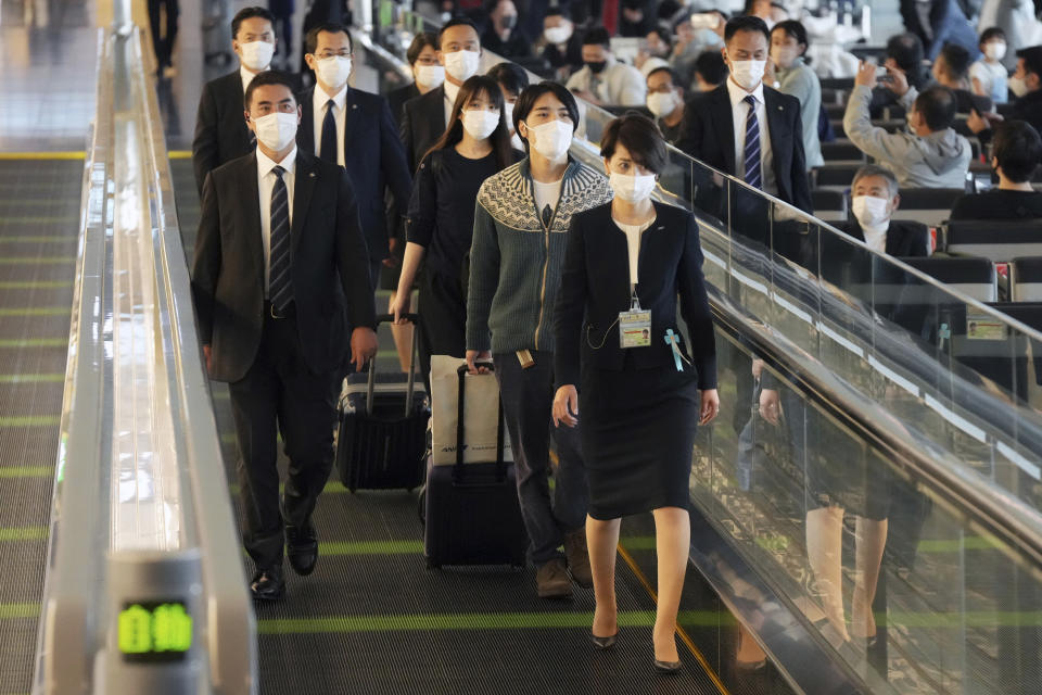 Japan's former Princess Mako, third right, the elder daughter of Crown Prince Akishino, and her husband Kei Komuro, second right, are escorted to board an airplane to New York Sunday, Nov. 14, 2021, at Tokyo International Airport in Tokyo. (AP Photo/Eugene Hoshiko)