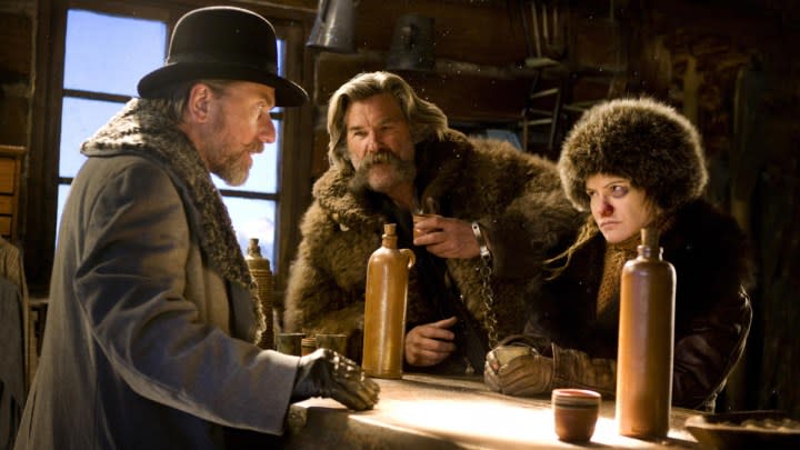 The cast of The Hateful Eight sits at a table.