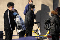 Medical workers in protective overalls walk past a line outside the fever clinic of a hospital in Beijing, Friday, Dec. 9, 2022. China began implementing a more relaxed version of its strict "zero COVID" policy on Thursday amid steps to restore normal life, but also trepidation over a possible broader outbreak once controls are eased. (AP Photo/Ng Han Guan)