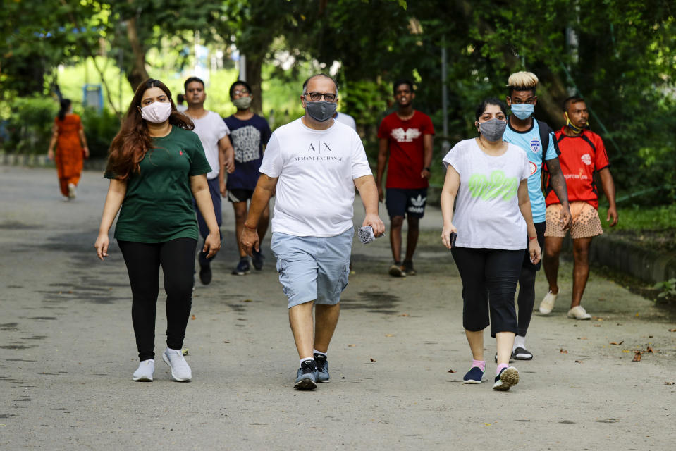 An Indian family followed by others take a walk in the morning wearing face masks to prevent the spread of the coronavirus inside a park in Kolkata, India, Tuesday, Sept. 15, 2020. India's coronavirus cases are now the second-highest in the world and only behind the United States. (AP Photo/Bikas Das)