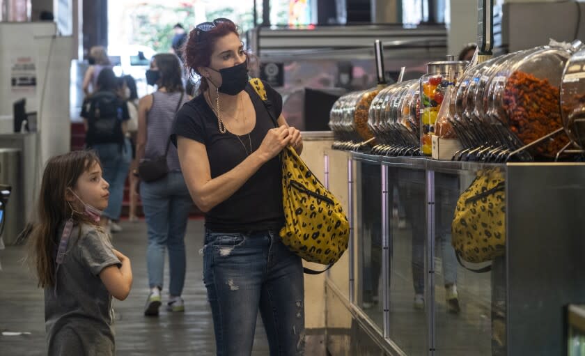 LOS ANGELES, CA - MARCH 01: Hesta Prynn, right, and seven year old daughter Zoe, left, are the afternoon at Grand Central Market on Tuesday, March 1, 2022 in Los Angeles, CA. Today more than half the customers were wearing masks at the market. California officials announced that face masks will no longer be required indoors starting Tuesday, as the state shifts to an "endemic" approach to the coronavirus. Masks will be "strongly recommended" for unvaccinated people in most indoor settings like shops, gyms, bars and movie theaters, but they will no longer be mandated by the state after Tuesday. (Francine Orr / Los Angeles Times)