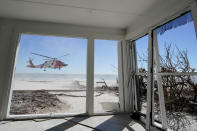 A U.S. Coast Guard helicopter takes off on Sanibel Island, Fla., with people affected by Hurricane Ian, as seen from inside a damaged home, Friday, Sept. 30, 2022. (AP Photo/Steve Helber)