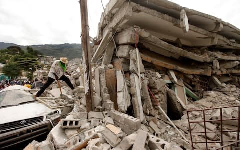 People work to free trapped victims from the rubble of a collapsed building after an earthquake in Port-au-Prince, Haiti.  - Credit: AP