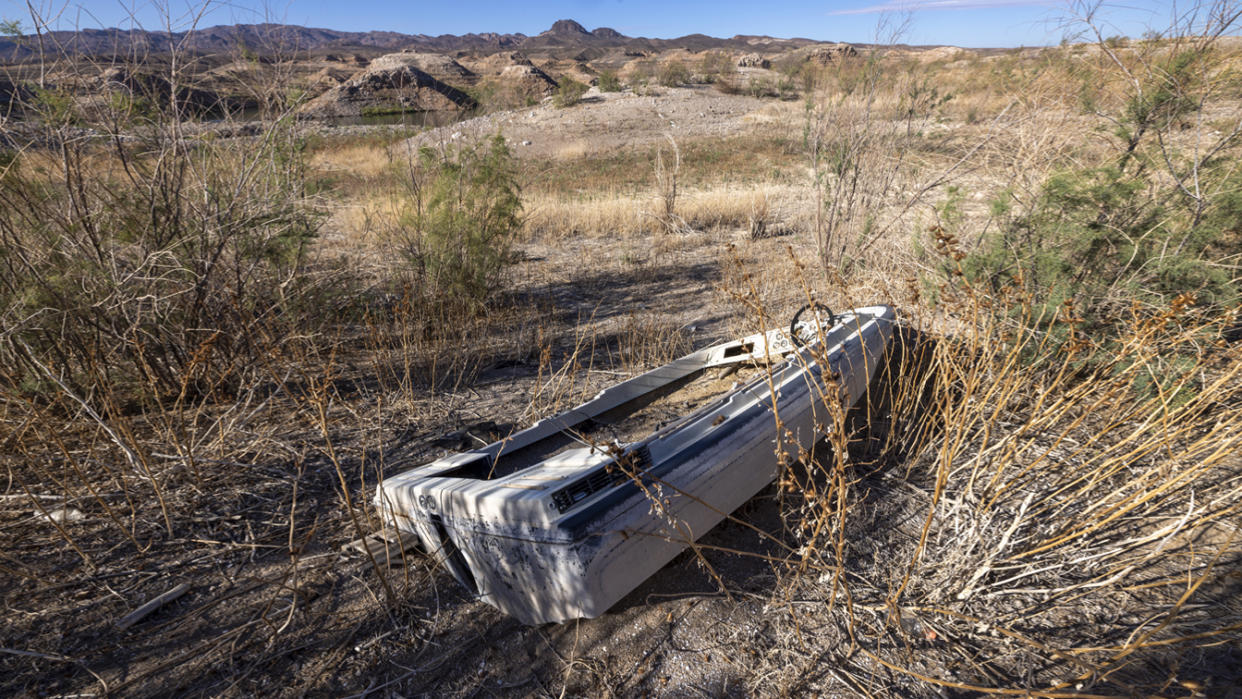 Caught in some tinder-dry brush, a sunken boat sits aslant on the dry lakebed.