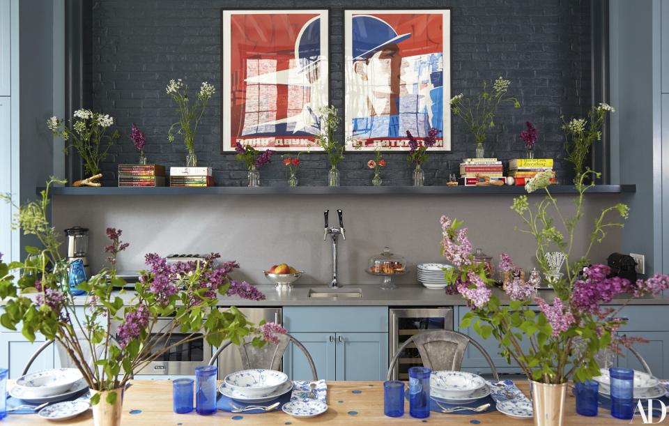 A vintage russian poster hangs on brick painted in Benjamin Moore’s Blacktop. Sparkling- and still-water tap by Crysalli. On the table, Royal Copenhagen dinnerware, Christofle flatware, and vintage glasses.