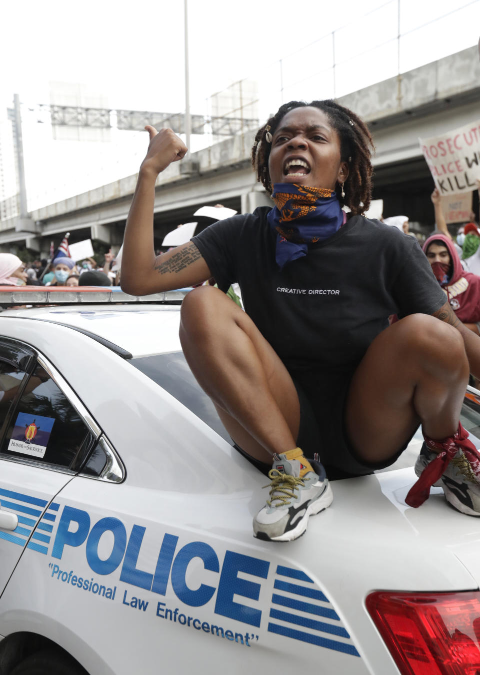 A protester sits on a police car as she yells at them during a demonstration next to the city of Miami Police Department, Saturday, May 30, 2020, downtown in Miami. Protests were held throughout the country over the death of George Floyd, a black man who died after being restrained by Minneapolis police officers on May 25.(AP Photo/Wilfredo Lee)