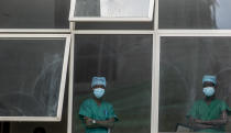 Medical staff look out from a window as officials prepare for a ceremony to commence the country's first coronavirus vaccinations using AstraZeneca COVID-19 vaccine manufactured by the Serum Institute of India and provided through the global COVAX initiative, at Kenyatta National Hospital in Nairobi, Kenya Friday, March 5, 2021. Urgent calls for COVID-19 vaccine fairness rang through African countries on Friday as more welcomed or rolled out doses from the global COVAX initiative, with officials acutely aware their continent needs much more. (AP Photo/Ben Curtis)