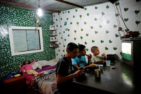 Doris Arocha (C), 30, who was sterilized two months ago, watches television with her children while they eat dinner at their home in San Diego, Venezuela July 19, 2016. REUTERS/Carlos Garcia Rawlins