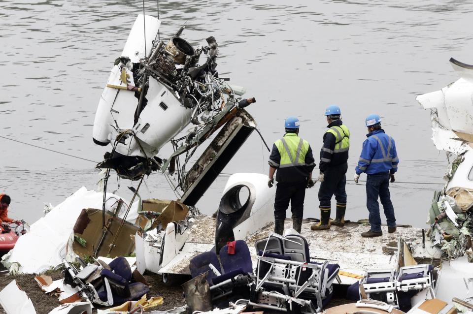 Rescuers look on as part of the wreckage of TransAsia Airways plane Flight GE235 is lifted after it crash landed into a river, in New Taipei City, February 5, 2015. Taiwanese rescue officials refused to give up hope of finding 12 people still missing on Thursday more than 24 hours after the TransAsia Airways plane crashed into a Taipei river, killing at least 31. REUTERS/Stringer (TAIWAN - Tags: TRANSPORT DISASTER) TAIWAN OUT. NO COMMERCIAL OR EDITORIAL SALES IN TAIWAN. CHINA OUT. NO COMMERCIAL OR EDITORIAL SALES IN CHINA