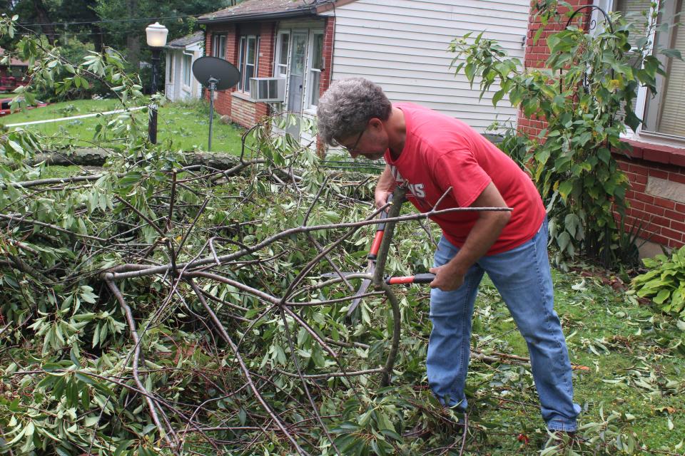 Steve Hays cleans up branches that fell outside Michelle Hildreth's home on Goodview Avenue in Akron.