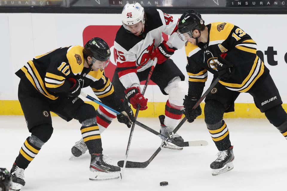 New Jersey Devils' Sami Vatanen (45) battles Boston Bruins' Anders Bjork (10) and Charlie Coyle (13) for the puck during the first period of an NHL hockey game, Sunday, March 28, 2021, in Boston. (AP Photo/Michael Dwyer)