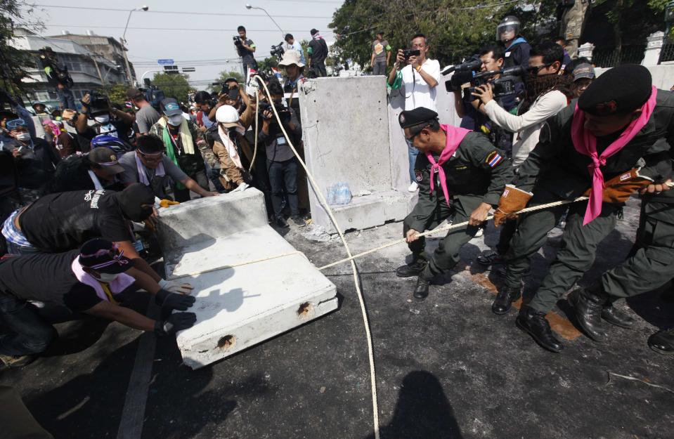 Riot police officers help anti-government protesters pull down a barricade near the metropolitan police headquarters in Bangkok December 3, 2013. Thailand's government ordered police to stand down and allow protesters into state buildings on Tuesday, removing a flashpoint for clashes and effectively bringing an end to days of violence in Bangkok in which five people have died. REUTERS/Kerek Wongsa (THAILAND - Tags: POLITICS CIVIL UNREST)