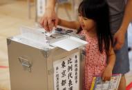 A girl helps to cast a ballot at a voting station during Japan's upper house election in Tokyo