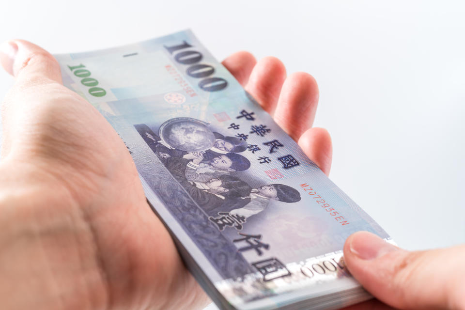 A hand holding a 1000 New Taiwan Dollar bill.