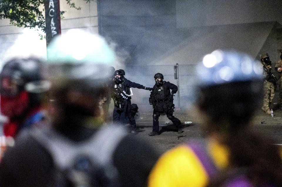 Federal officers prepare to disperse Black Lives Matter protesters at the Mark O. Hatfield United States Courthouse on Tuesday, July 21, 2020, in Portland, Ore. A federal judge is hearing arguments on Oregon's request for a restraining order against federal agents who have been sent to the state's largest city to quell protests that have spiraled into nightly clashes between authorities and demonstrators. (AP Photo/Noah Berger)