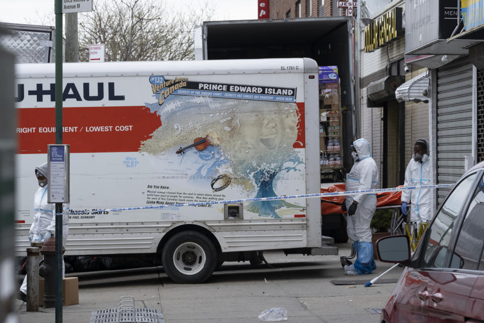 Workers move a body near the Andrew T. Cleckley Funeral Home in the Brooklyn borough of New York, Wednesday, April 29, 2020. Police responded to a report of human bodies in vehicles, which they determined were connected to the nearby funeral home. The New York Police Department notified the state Department of Health, which oversees funeral homes. The coronavirus pandemic has overrun most funeral homes and morgues in New York City. (AP Photo/Craig Ruttle)