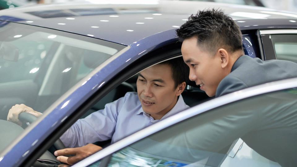 Salesman explaining car characteristics to customer.