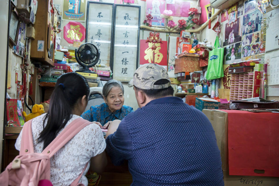 Image: A fortune teller with customers at a stall near the Wong Tai Sin Temple in Hong Kong. (Isaac Lawrence / AFP via Getty Images file)