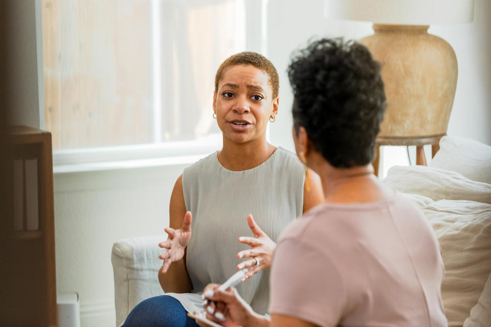 two women sitting on a couch talking to each other