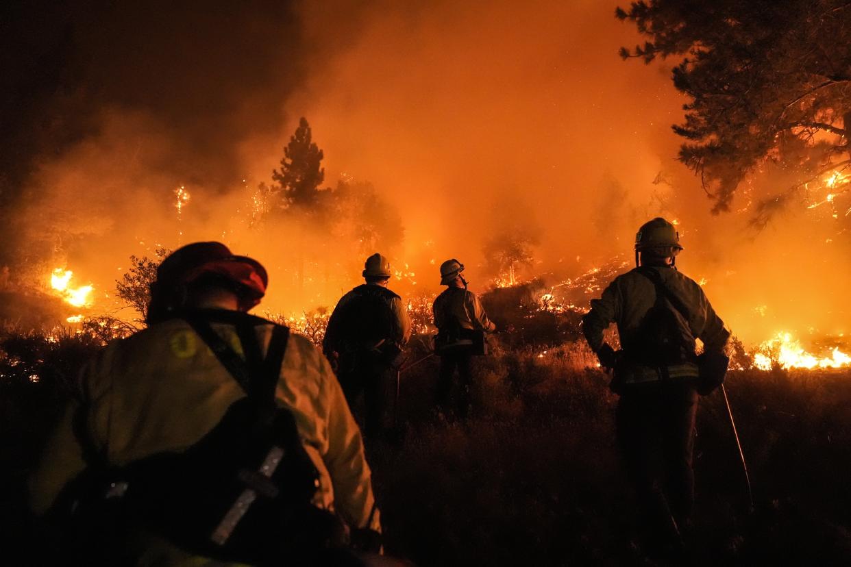 Firefighters watch as the Bridge Fire burns near homes in Wrightwood, Calif. on Sept. 10.