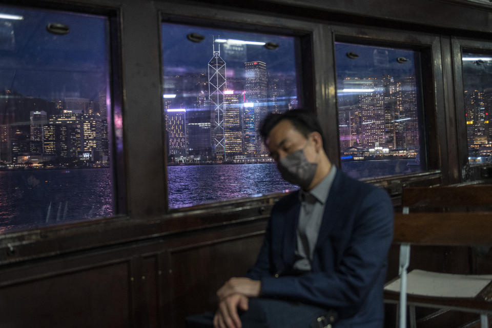 FILE - The city skyline is seen as a man naps on the Star Ferry in Hong Kong, on Oct. 19, 2022. The exodus of tens of thousands of professionals from Hong Kong triggered by Beijing's crackdown on its civil liberties is being offset by new arrivals: mainland Chinese keen to move to the former British colony. (AP Photo/Vernon Yuen, File)
