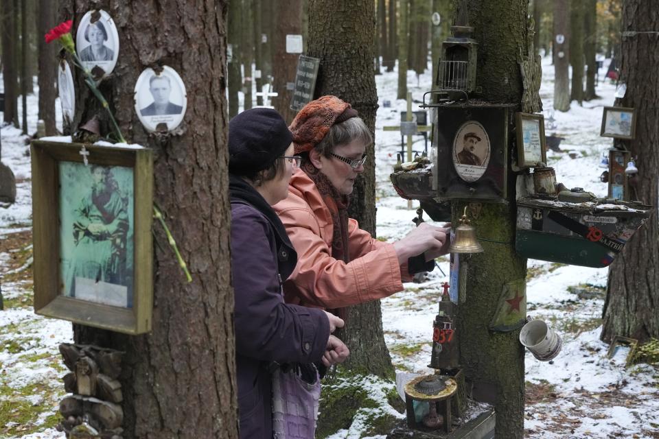 FILE - Women attach a portrait of a relatives to a tree as people gather at Levashovo Cemetery outside St. Petersburg, Russia, on Monday, Oct. 30, 2023, to commemorate victims of Soviet repression under dictator Joseph Stalin. About 45,000 of the victims were buried in the cemetery from 1937 to 1953. In December 2021, a Moscow court ordered the closure of the human rights group Memorial, which drew international acclaim for highlighting repression in the Soviet Union. (AP Photo, File)
