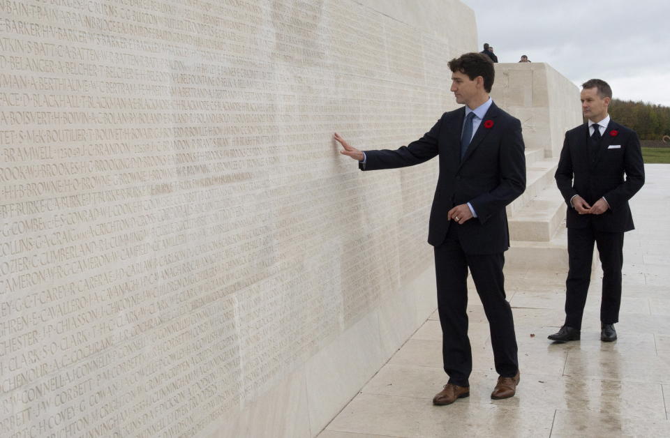 Canada's Minister of Veterans Affairs Seamus O'Regan looks on as Canadian Prime Minister Justin Trudeau touches the names of fallen soldiers engraved in the Canadian National Vimy Memorial, Saturday Nov. 10, 2018 at Vimy Ridge, France. (Adrian Wyld/The Canadian Press via AP)